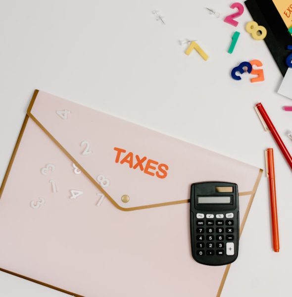 Flat lay of a tax preparation workspace with calculator, envelope, and colorful numbers.